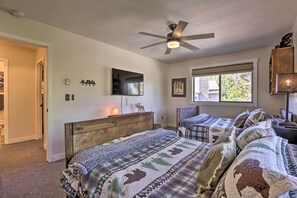 Une chambre avec deux lits, un ventilateur de plafond, une télévision et une fenêtre donnant sur un beau paysage.