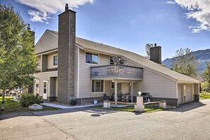 Une maison à deux étages dotée d’un balcon, d’une cheminée et d’un patio aménagé avec du mobilier d’extérieur.