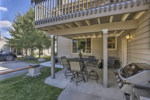 Un patio couvert avec un barbecue, des sièges d’extérieur et une vue sur la rue.