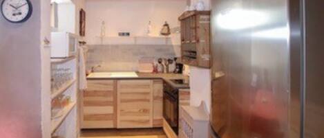 A compact kitchen with wooden cabinets, a stainless steel refrigerator, and a small countertop.
