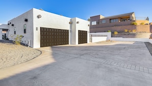 Una casa moderna de dos pisos con garaje, entrada para vehículos y un jardín con plantas pequeñas.