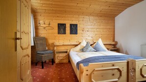Une pièce aux murs lambrés, contenant un lit, une chaise et une armoire.