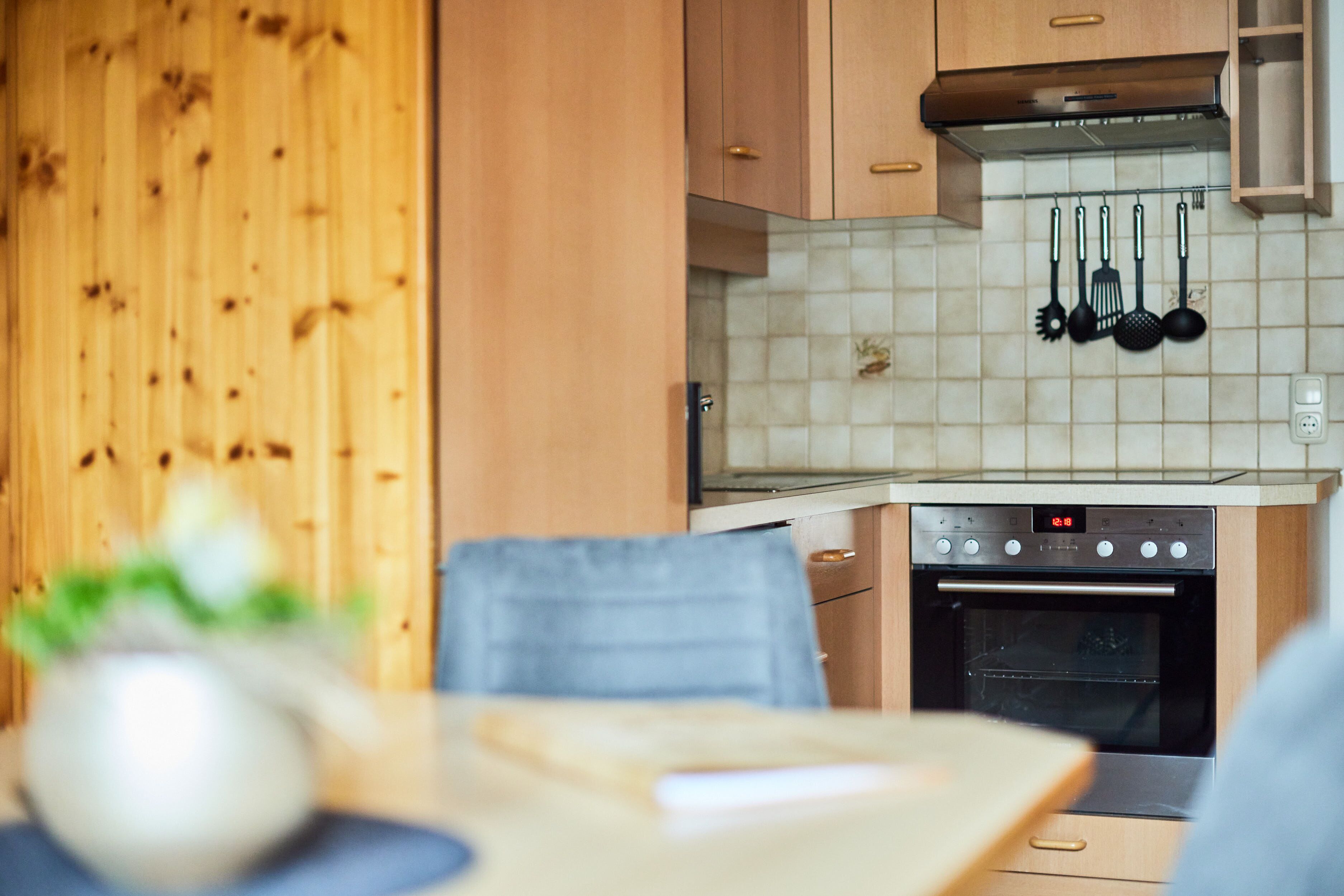 Eine Küche mit Holdekor-Schränken, einer Fliesenrückwand und einem Edelstahlbackofen.