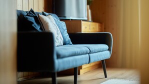 Un salon moderne avec un canapé, un téléviseur à écran plat et un lambris en bois.