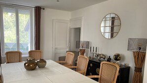 A dining room with a long table, wicker chairs, and decorative items. - GITE***** DE LUXE VOSGES: CHEZ LIVIA (Bruyères)