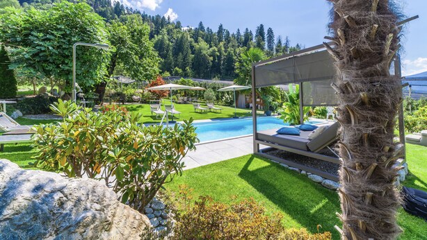 A pool area with lounge chairs, a covered seating area, and a view of a mountainous landscape. - Apartment "Sonnenblume" with Mountain View, Pool, Wi-Fi, Balcony & Garden (Rifiano)