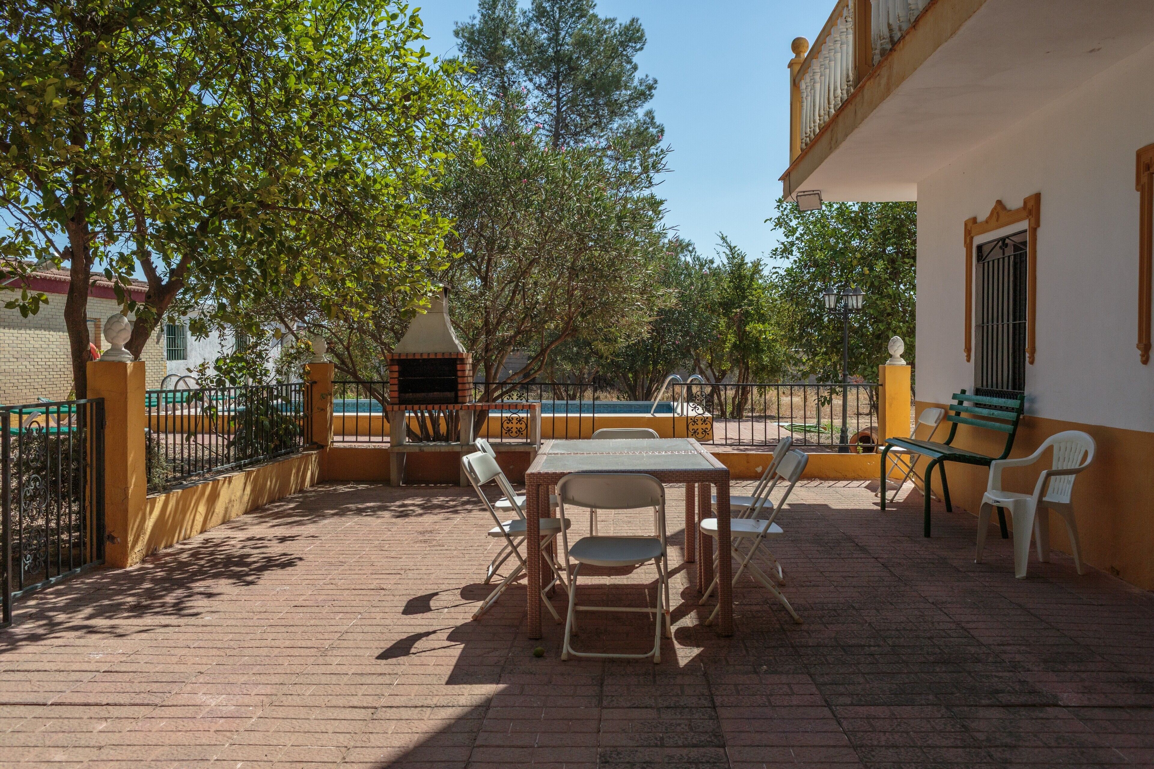 Un patio al aire libre con una mesa y sillas, un pequeño pabellón y una piscina.