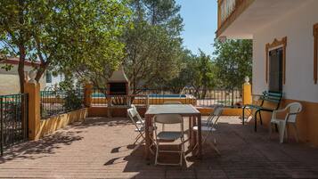 Un patio al aire libre con una mesa y sillas, un pequeño pabellón y una piscina.