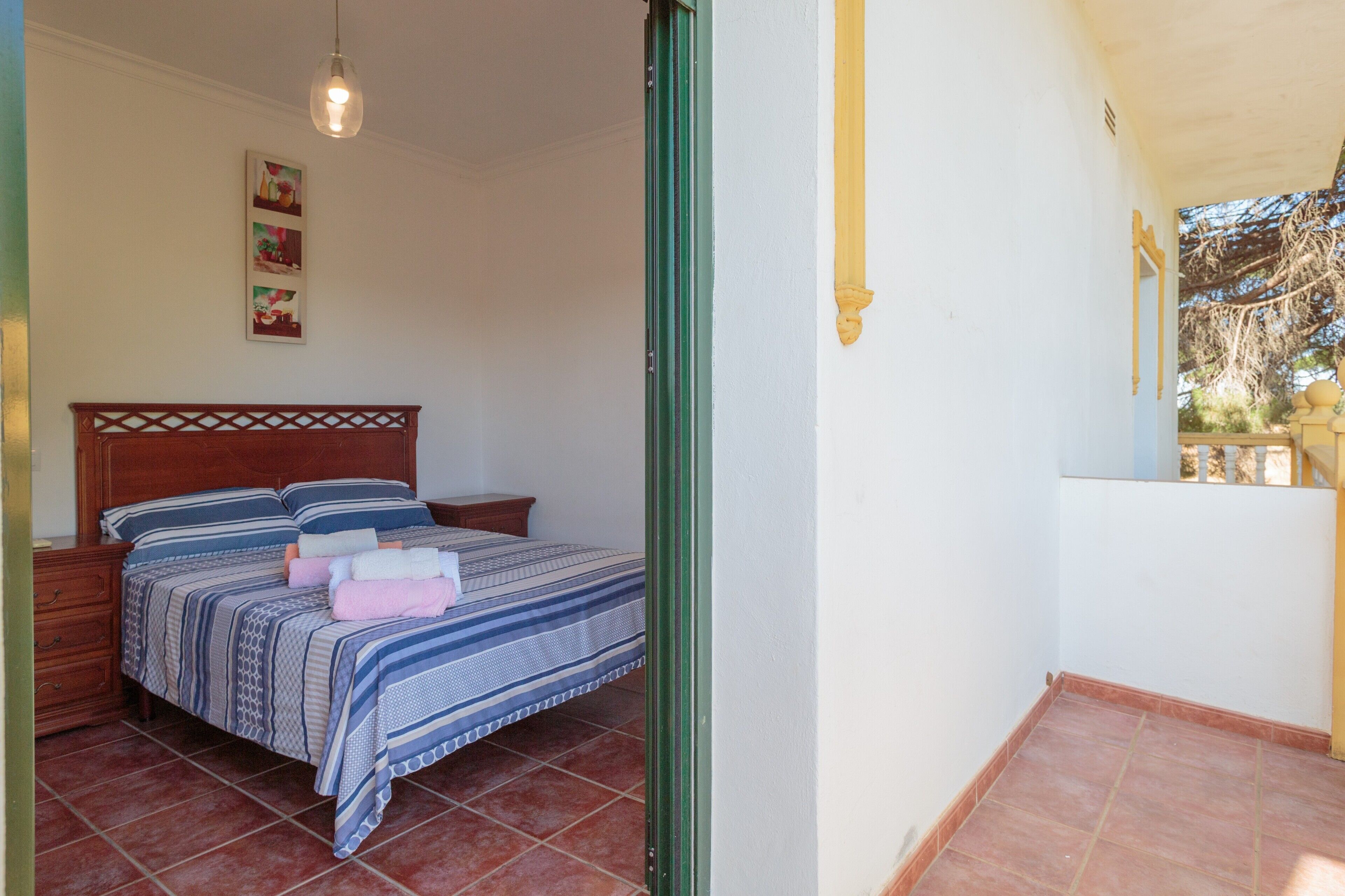 Una camera da letto con un letto, un comodino, una lampada a sospensione e un quadro appeso al muro.