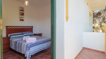 Una camera da letto con un letto, un comodino, una lampada a sospensione e un quadro appeso al muro.