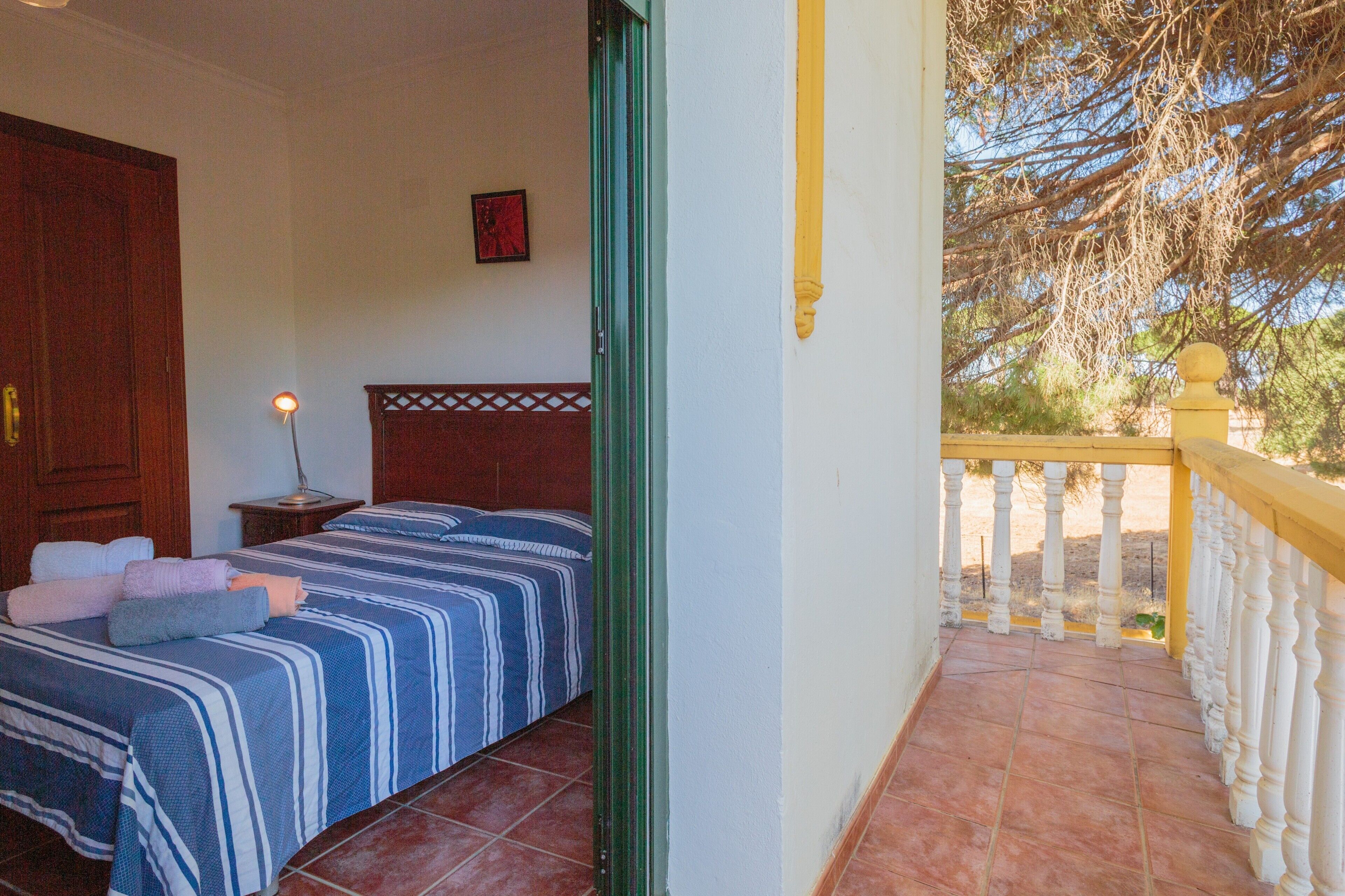 Un dormitorio con cama, mesita de noche y vistas al exterior.