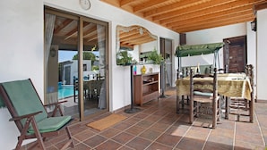 Une terrasse couverte avec une piscine, des meubles en bois et une table à manger.