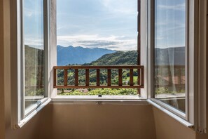 Ein Zimmer mit Fensterblick auf eine gebirgige Landschaft.