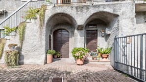 Un bâtiment doté de deux portes cintrées, d’une entrée pavée et de plantes en pot.