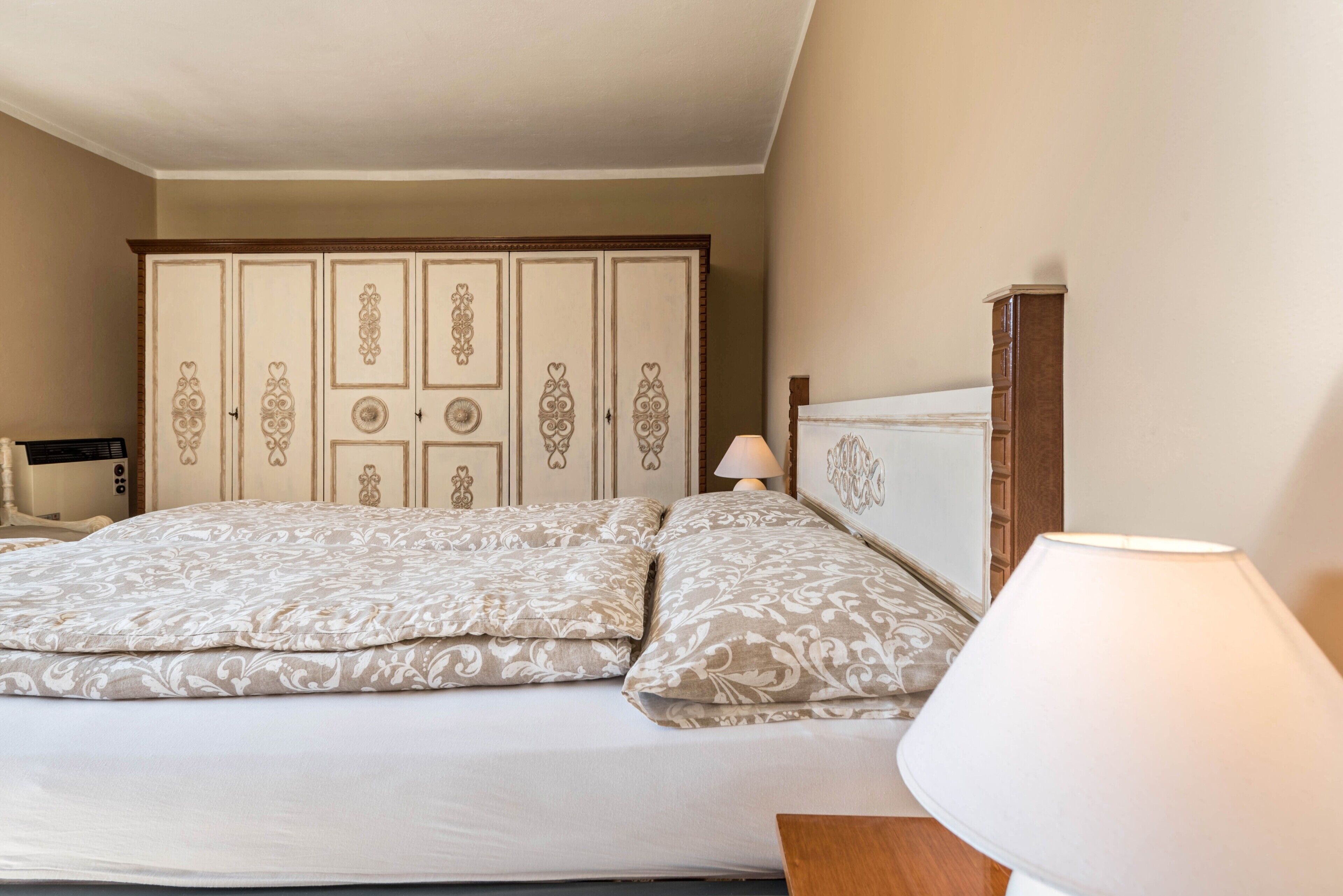 Een slaapkamer met een bed, twee bedlampen, een kledingkast en een nachtkastje.