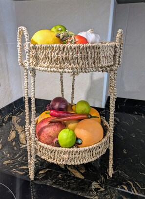 A woven fruit basket on a marble countertop.