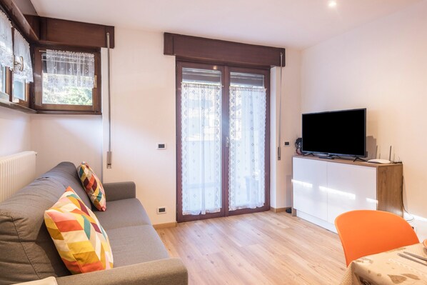 Een woonkamer met een bank, een televisie, een tafel en een stoel.