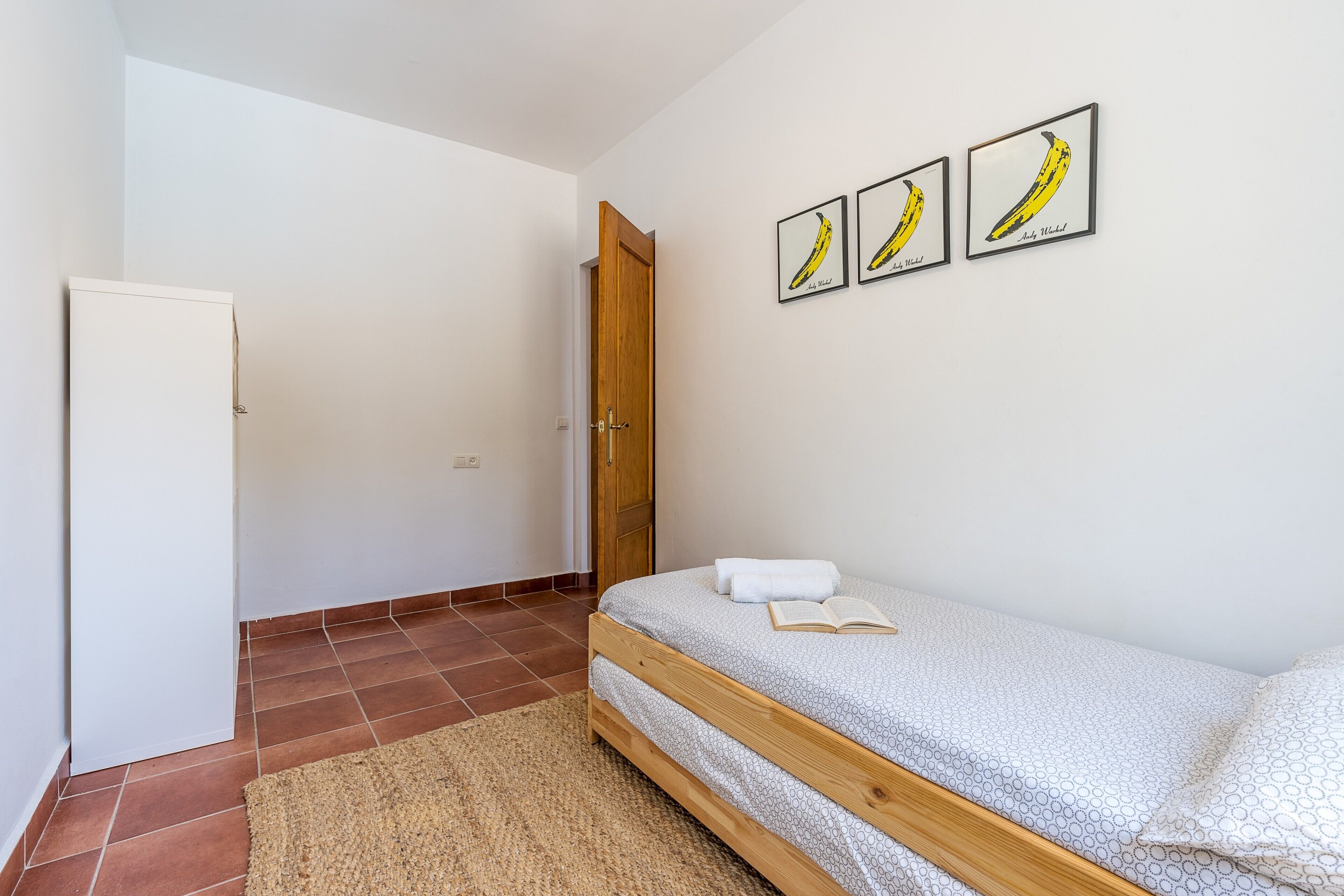 A bedroom with a bed, a door, and three framed pictures on the wall.