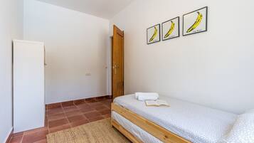 A bedroom with a bed, a door, and three framed pictures on the wall.