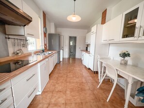 A kitchen with white cabinets, a wooden countertop, a sink, and a hanging light fixture.