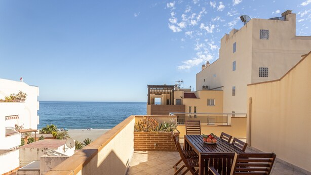 A terrace with a table and chairs, a brick planter with plants, and a view of the sea. - Penthouse "Mediterranean Attic" Near the Beach with Sea Views, Balcony, and Wi-Fi (Almuñecar)