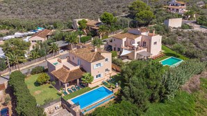 A residential property with a swimming pool, multiple buildings, and surrounding greenery.