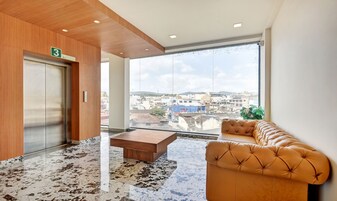 Un vestíbulo moderno con suelo de mármol, un mostrador de recepción de madera, un sofá y un amplio ventanal con vistas a la ciudad.