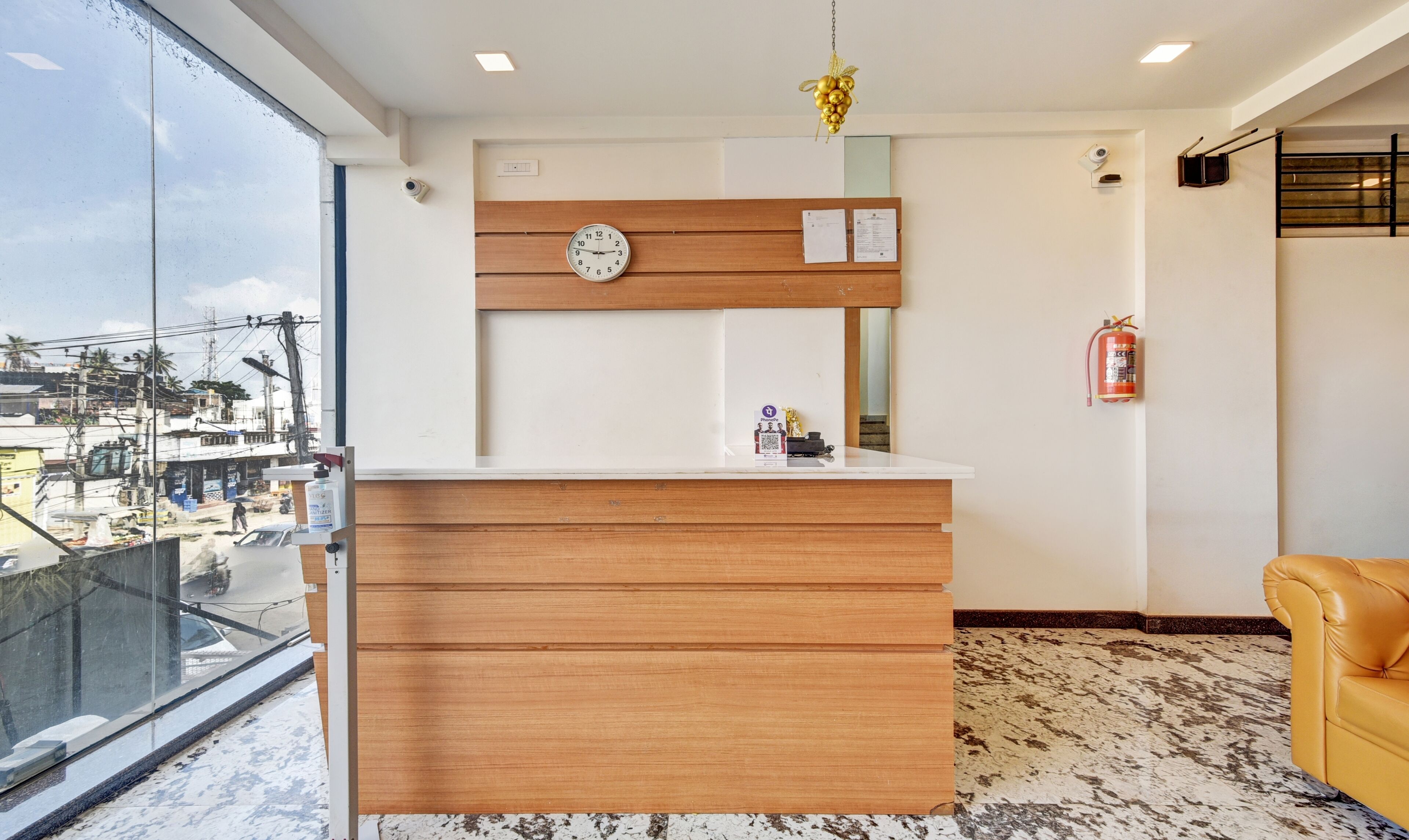 A reception desk with a clock, a small plaque, and a fire extinguisher on the wall.