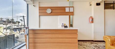 A reception desk with a clock, a small plaque, and a fire extinguisher on the wall.