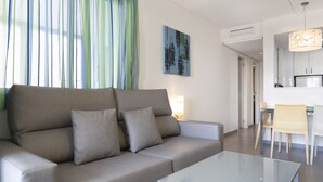 A modern living room with a grey sofa, a glass coffee table, and a dining area with a white table and chairs. - First line / Wifi / Spa / Seaviews / Heated pool / Pets (Calpe)