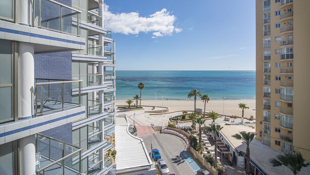 Ein Hochhotel mit zahlreichen Balkonen mit Blick auf Strand und Meer.