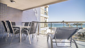 Een balkon met een tafel en stoelen, met uitzicht op de oceaan.