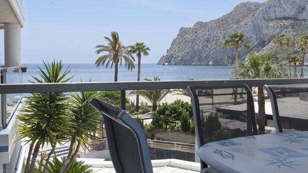 A balcony with a view of the sea, palm trees, and a rocky cliff. - First line / Wifi / Spa / Seaviews / Heated pool / Pets (Calpe)