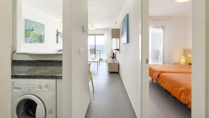 A hotel corridor with a washing machine, a dining area, and a bedroom with an orange bedspread. - First line / Wifi / Spa / Seaviews / Heated pool / Pets (Calpe)