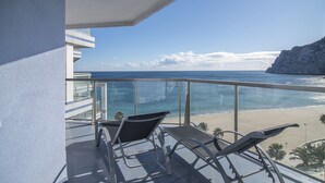 Un balcón con dos sillones de relax con vistas a una playa y el océano.