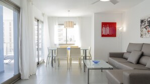 A modern living room with a sofa, a coffee table, and a dining area with chairs and a table.