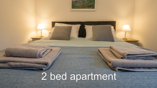 Eine Zwei-Zimmer-Wohnung mit einem Bett, Kissen und einem Bild an der Wand.