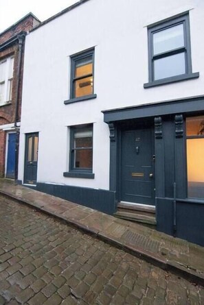 A two-story building with a white facade and dark trim around the windows and doors. - Heart of Macclesfield 2 Bedroom Grade II Apartment (Macclesfield)