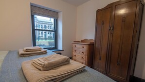 A 2 bed apartment with a large window, a wardrobe, and a bed with folded towels. - Heart of Macclesfield 2 Bedroom Grade II Apartment (Macclesfield)