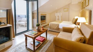 A hotel room with a balcony, a sofa, a bed, a TV, and a coffee table with books. - Delita City Hotel (Istanbul)