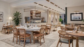 A modern dining area with round tables, wooden chairs, and a bar area with shelves of bottles. - Delita City Hotel (Istanbul)