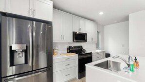 A modern kitchen with stainless steel appliances, white cabinetry, and a built-in oven. - Anders' sweet suite - Micro Studio - 91Walkscore (Seattle)