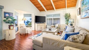Amplia sala de estar con techo de madera, televisor de pantalla plana y un ventanal con vistas a un balcón.