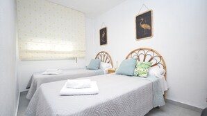 Een hotelkamer met twee bedden, elk met een houten hoofdbord, wit beddengoed en een klein nachtkastje met een lamp.