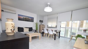 Een moderne woonkamer met een bank, salontafel en een eethoek met stoelen.