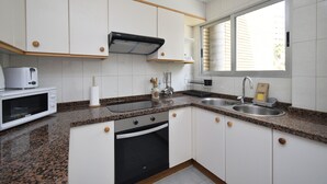 Een keuken met witte kasten, een granieten aanrecht, een magnetron, een fornuis en een spoelbak.