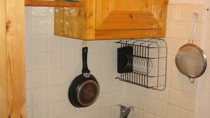 Una cocina con armarios de madera, un fregadero, una estufa y utensilios colgantes.