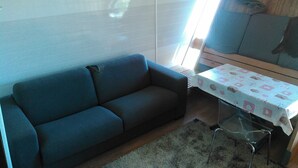 Una habitación con un sofá, una mesa con mantel y una ventana con persianas.