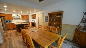A spacious kitchen with wooden cabinets, a large dining table, and a built-in bookshelf. - Walter Lake Area, Gated Community with Pool (Bass Lake)