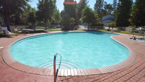 A circular pool with a brick border, surrounded by trees and a fence. - Walter Lake Area, Gated Community with Pool (Bass Lake)